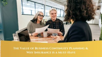 A middle-aged couple smiling and holding documents as they discuss plans with a professional across the table. The image includes a banner at the bottom that reads, "The Value of Business Continuity Planning & Why Insurance is a Must-Have."