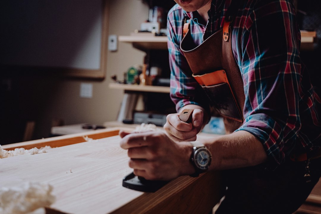 Close-up of a person's hands using a tape measure on a wooden workbench, illustrating the importance of measuring marketing results for a local business.